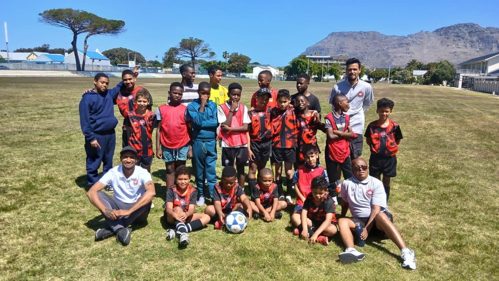 FS4 players and coaches posing together on the pitch with the Cape Town mountains in the background